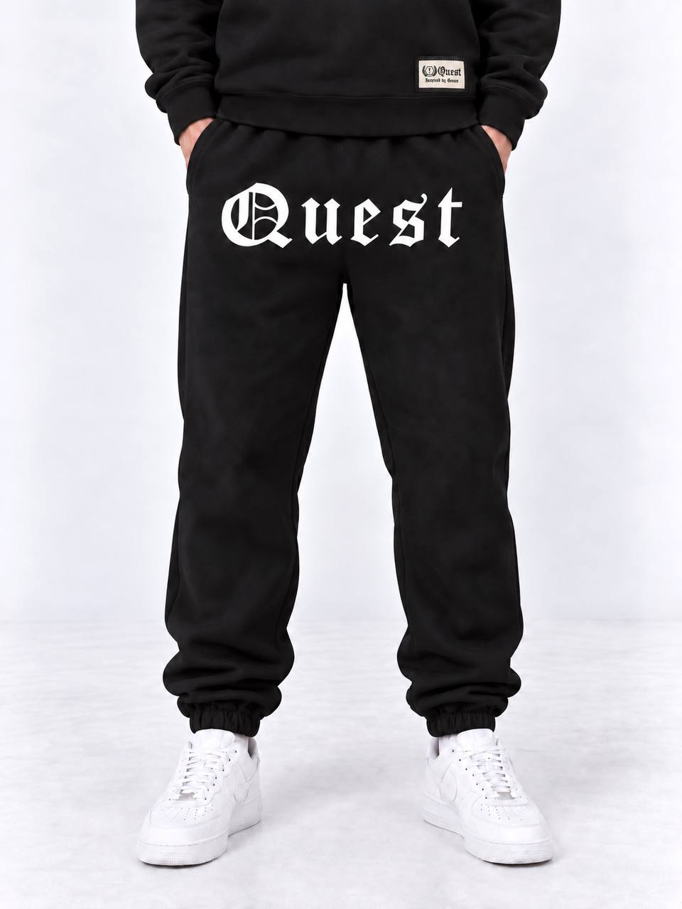 Black cuffed joggers with white blackletter Quest thigh print
